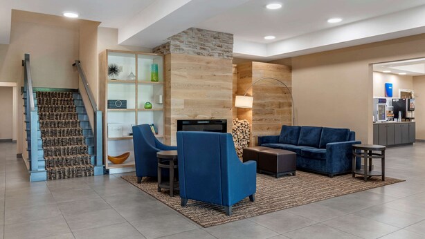 A modern lobby with a staircase, seating area, and a kitchen in the background. - Comfort Inn & Suites Millbrook - Prattville (Millbrook)