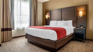A hotel room with a large bed, two bedside lamps, a nightstand, and a window with curtains. - Comfort Inn & Suites Millbrook - Prattville (Millbrook)