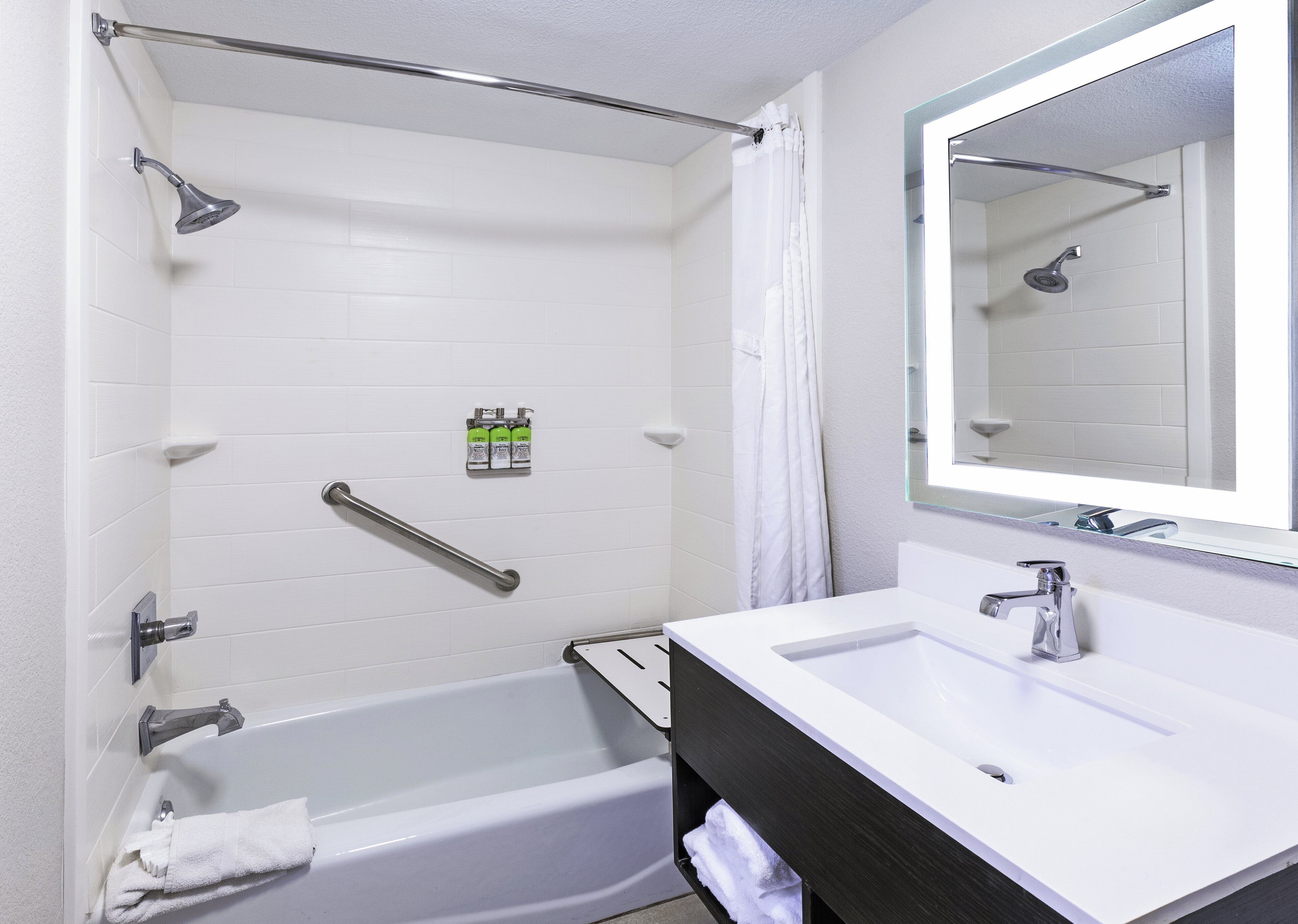 A bathroom with a bathtub, a shower, a vanity with a mirror, and a towel rack.