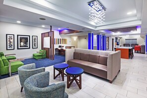 A hotel lobby with seating areas, a reception desk, and artwork on the walls.