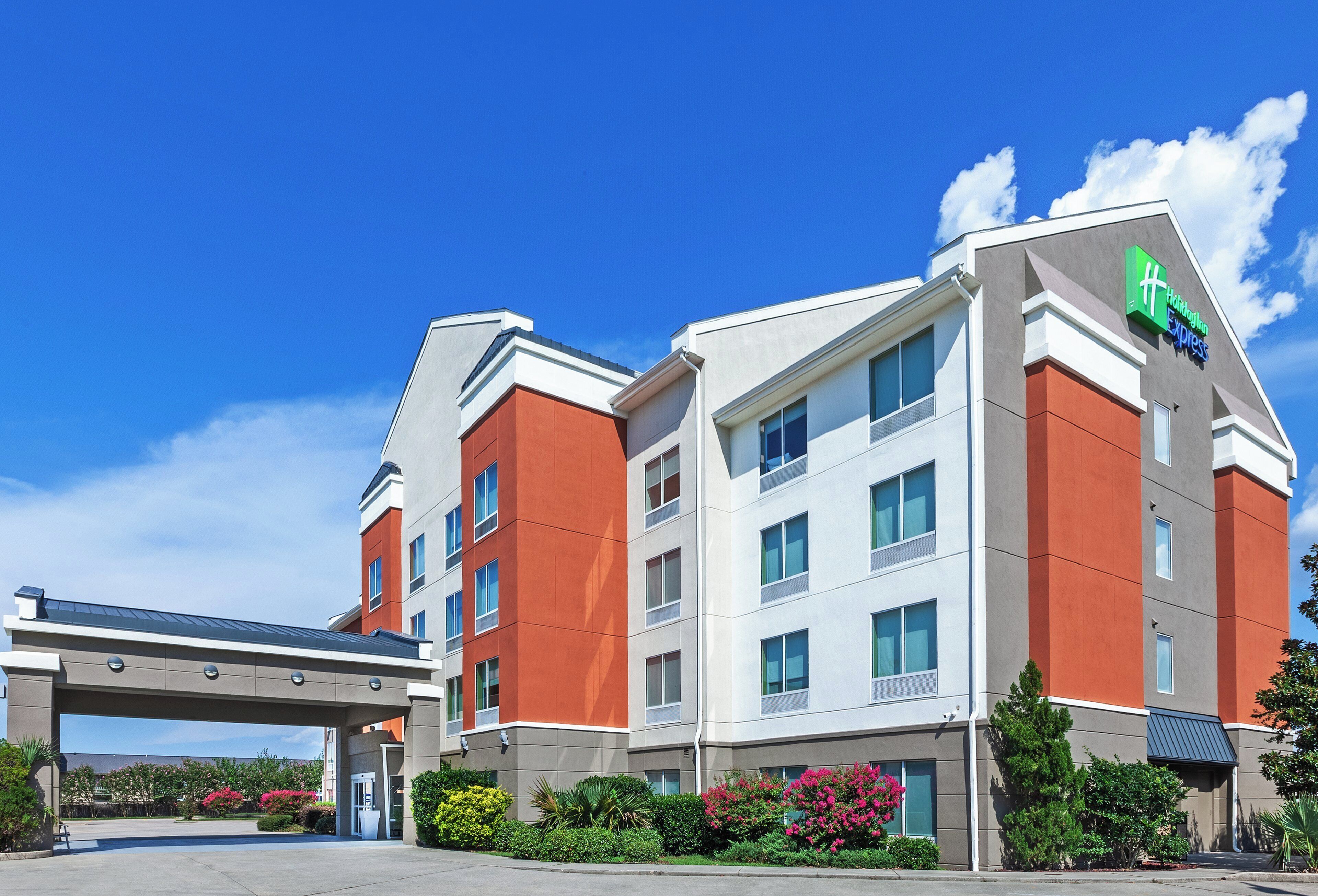 A multi-story hotel with a modern design, featuring a prominent green and blue sign indicating it is a Holiday Inn Express.