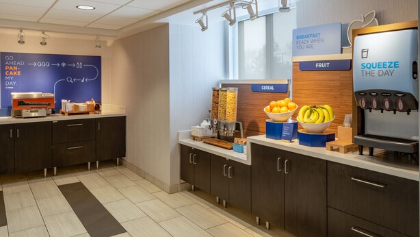 A modern breakfast area with a self-serve station, including a coffee machine, cereal, and fruit options. - Holiday Inn Express New Orleans East by IHG (New Orleans)