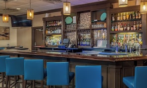 A bar area with a counter, bar stools, and shelves stocked with bottles and glasses. - Holiday Inn Conference Ctr Marshfield by IHG (Marshfield)