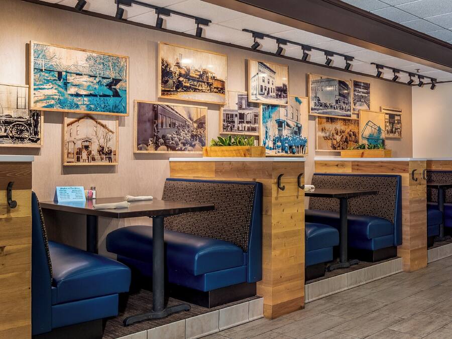 A restaurant interior with wooden booths, black cushioned seating, and wall-mounted artwork.