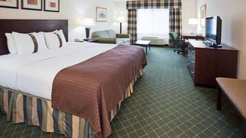 A hotel room with a large bed, a desk, a television, and a chair.