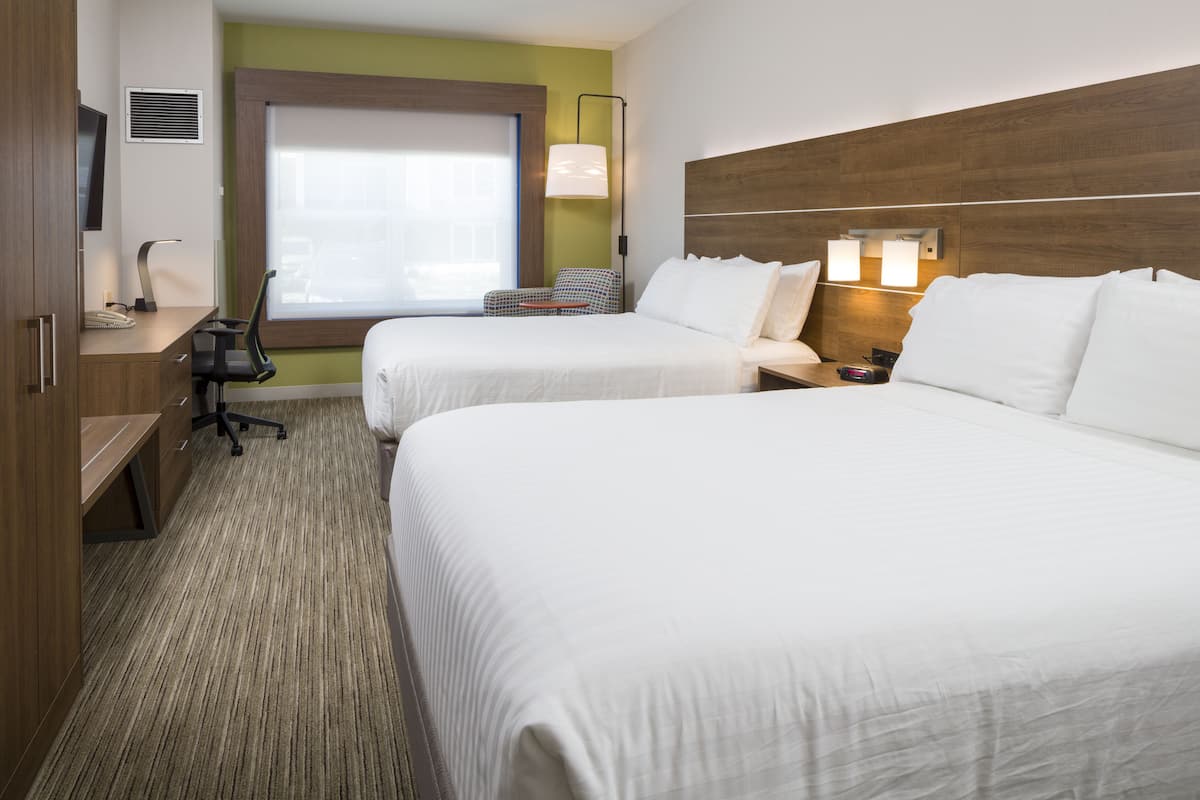 Une chambre d’hôtel avec deux lits, un bureau, une chaise et une télévision.