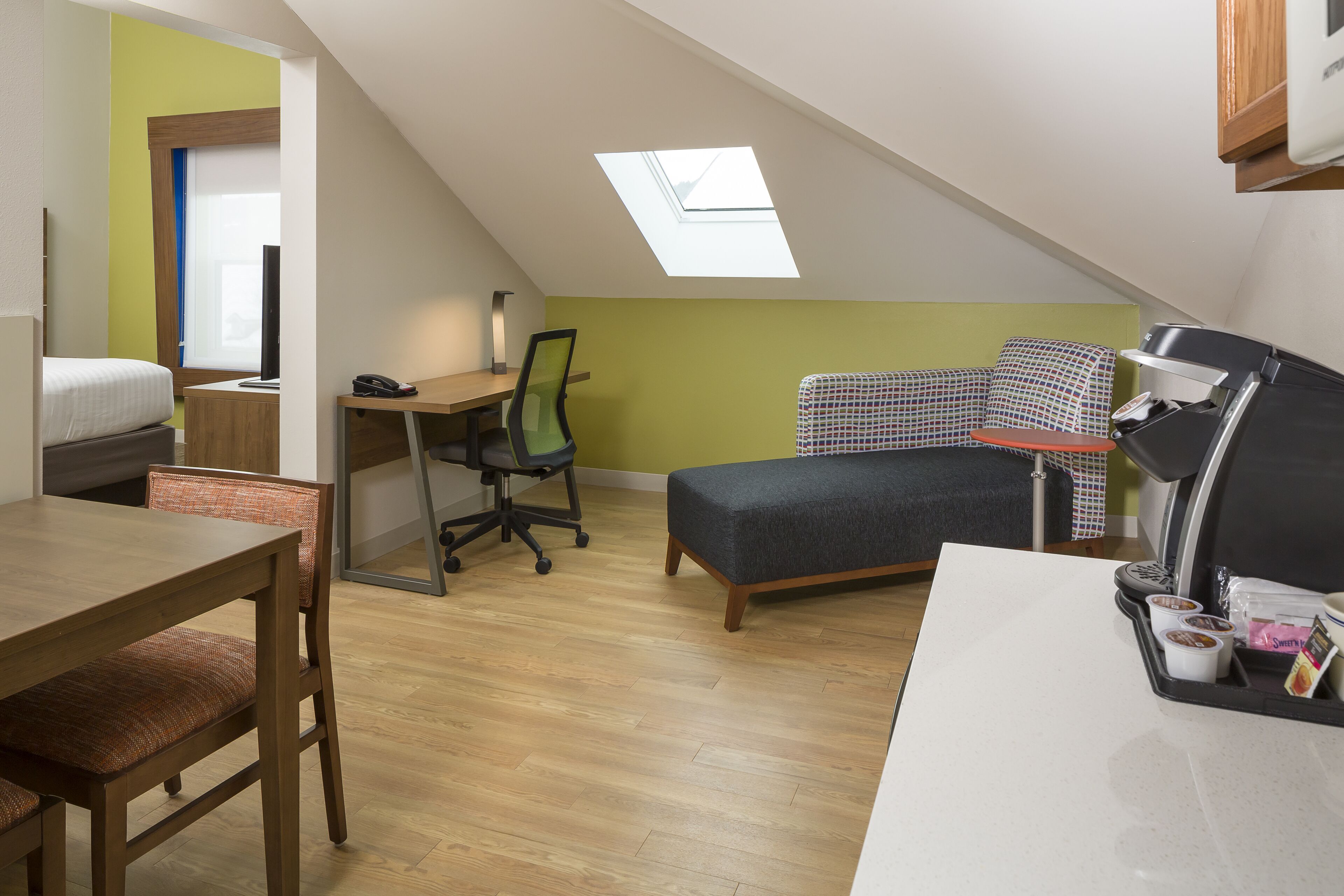 A compact room with a loft bed, a desk, and a dining table.