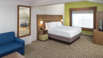 A hotel room with a bed, a desk, a chair, a nightstand, a mirror, and a window.