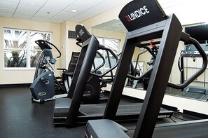 Une salle de sport équipée de divers appareils d’exercice, notamment des tapis de course et des appareils de musculation.
