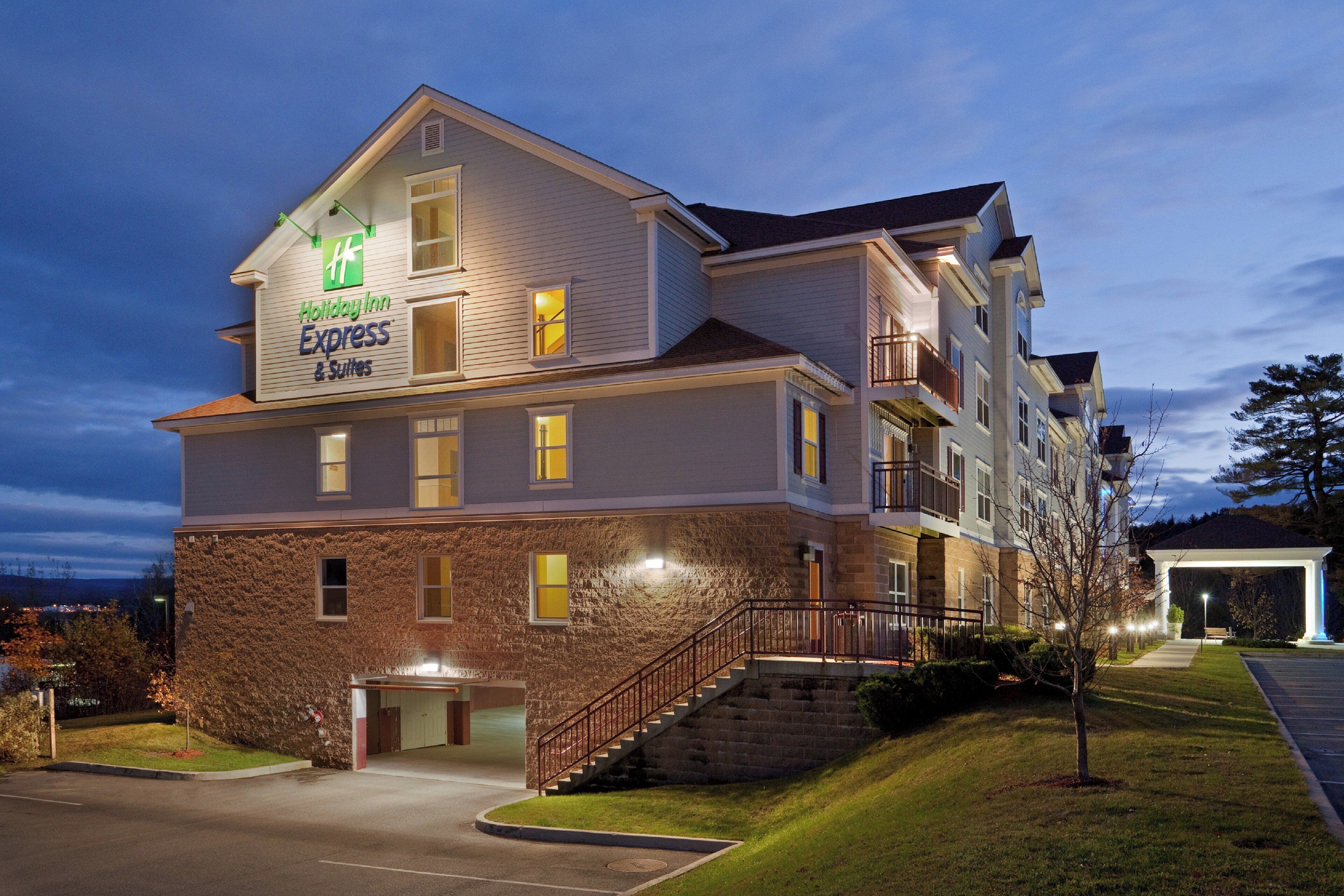 Monikerroksinen Holiday Inn Express & Suites -hotelli, jossa on tiiliverhous, katettu pysäköintialue ja hyvin valaistu sisäänkäynti.