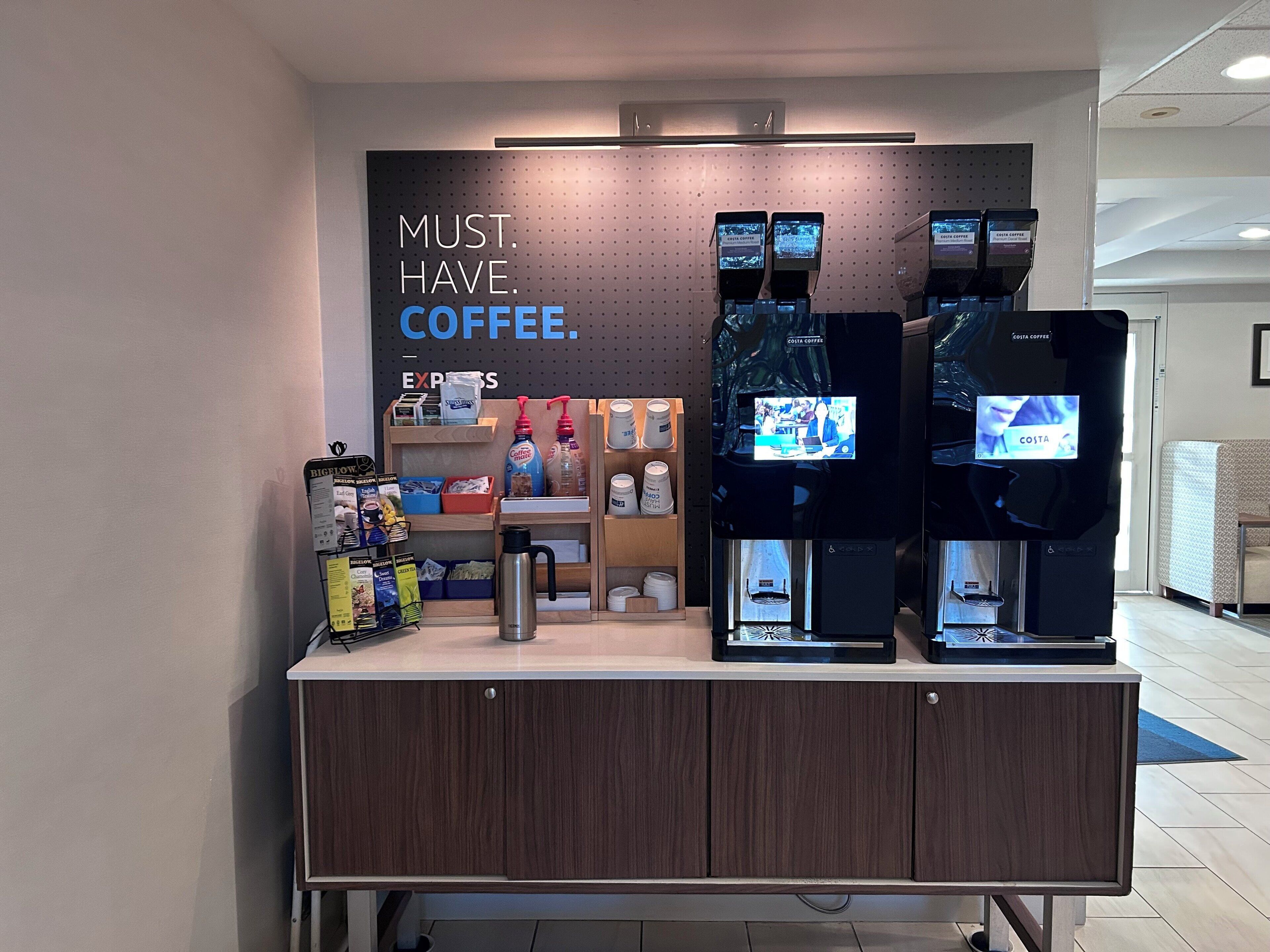 A coffee station with multiple coffee dispensers and a sign that reads "MUST HAVE COFFEE."