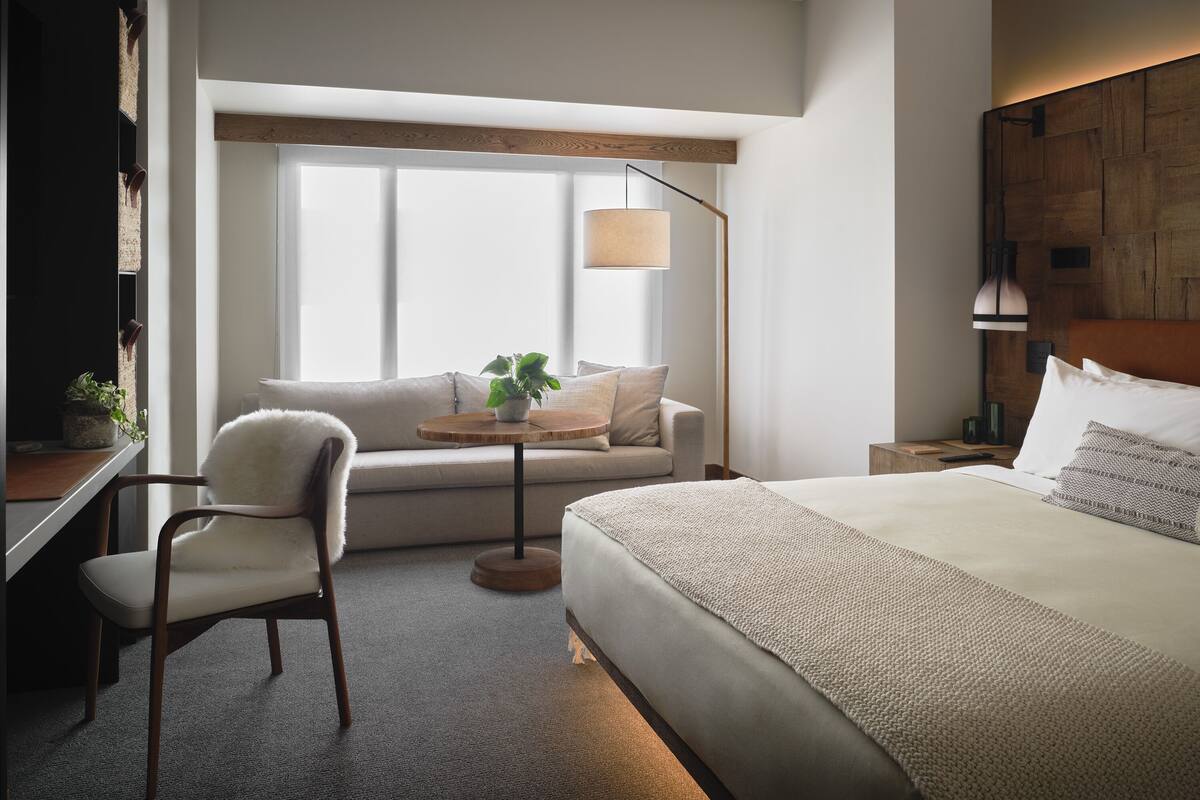 Ein modernes Hotelzimmer mit Bett, Sofa, Schreibtisch und Fenster.