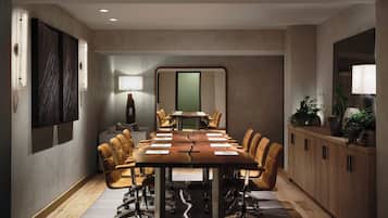 A conference room with a long table, chairs, a lamp, and a cabinet with plants.