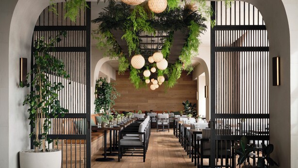 Un restaurante con suelo de madera, sillas negras, mesas blancas, plantas colgantes y lámparas colgantes.