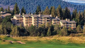 Ein Resort mit mehreren Gebäuden, einem Golfplatz und einem bewaldeten Berg im Hintergrund.