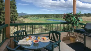 Ein Balkon mit Frühstückstisch, Grill und herrlichem Blick auf einen See und Berge.
