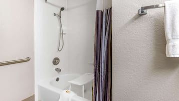 A bathroom with a shower, a bathtub, a towel rack, and a handrail.