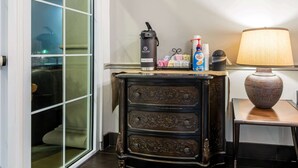 A room with a sliding glass door, a black cabinet with ornate carvings, a table lamp, and a small table with a vase. - La Quinta Inn by Wyndham San Antonio Brooks City Base (San Antonio)