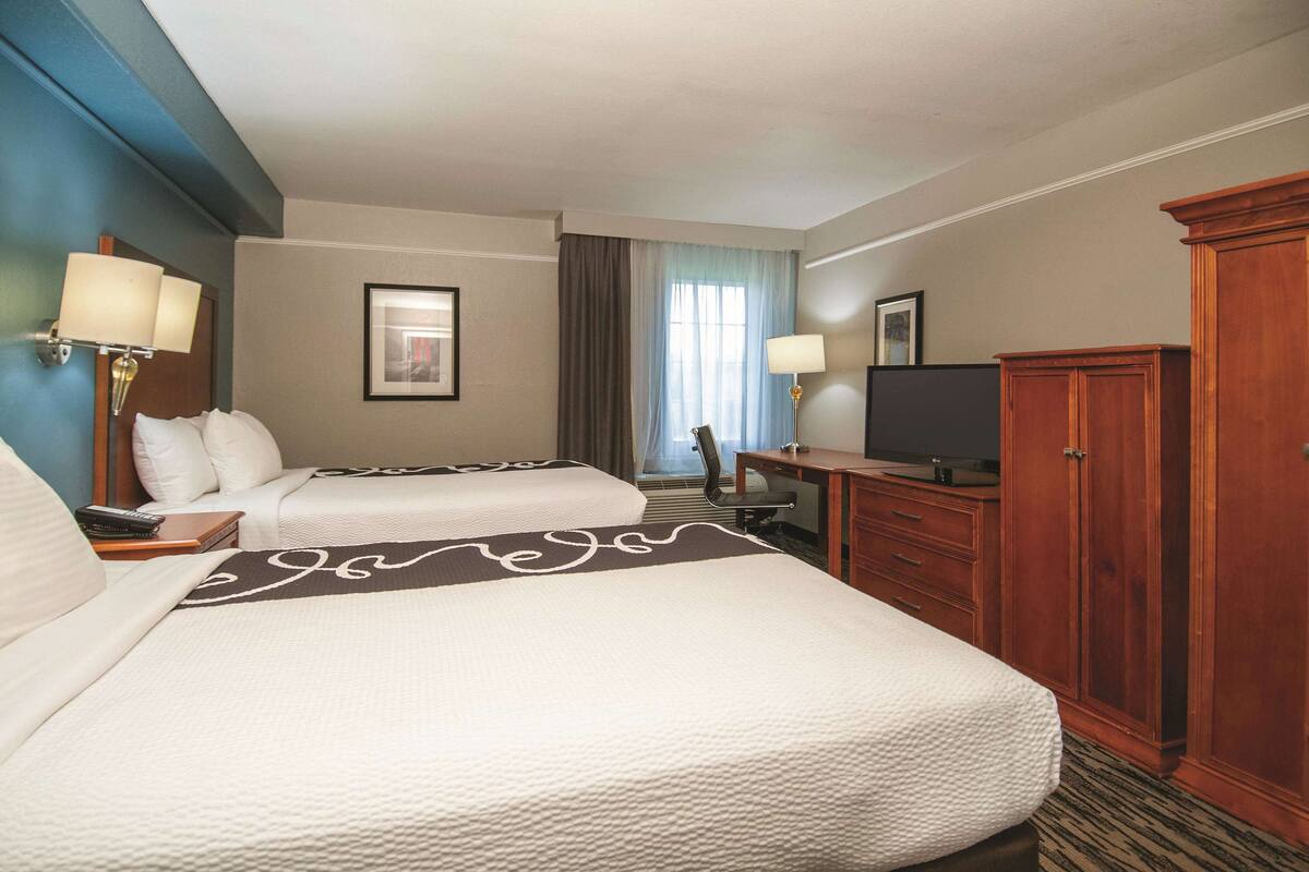 A hotel room with two beds, a desk, a television, and a wardrobe.