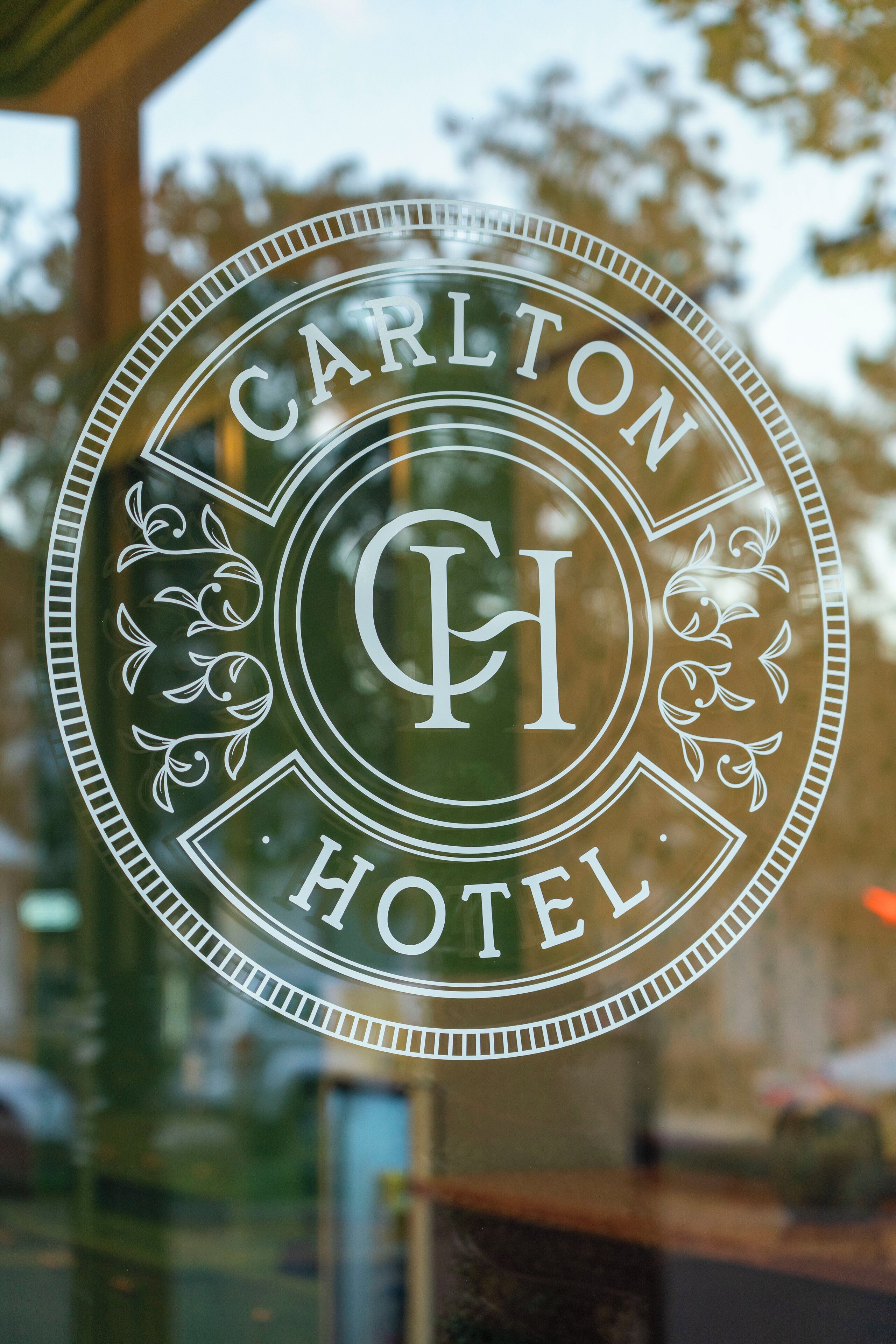 A circular logo with the text "Carlton Hotel" and a central emblem.