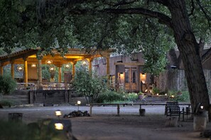 A rustic wooden building with a covered patio area, outdoor seating, and a pond. - The Abiquiu Inn (Abiquiu)