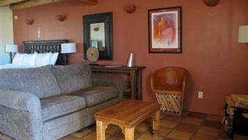 A living room with a sofa, a wooden coffee table, a chair, and a painting on the wall.