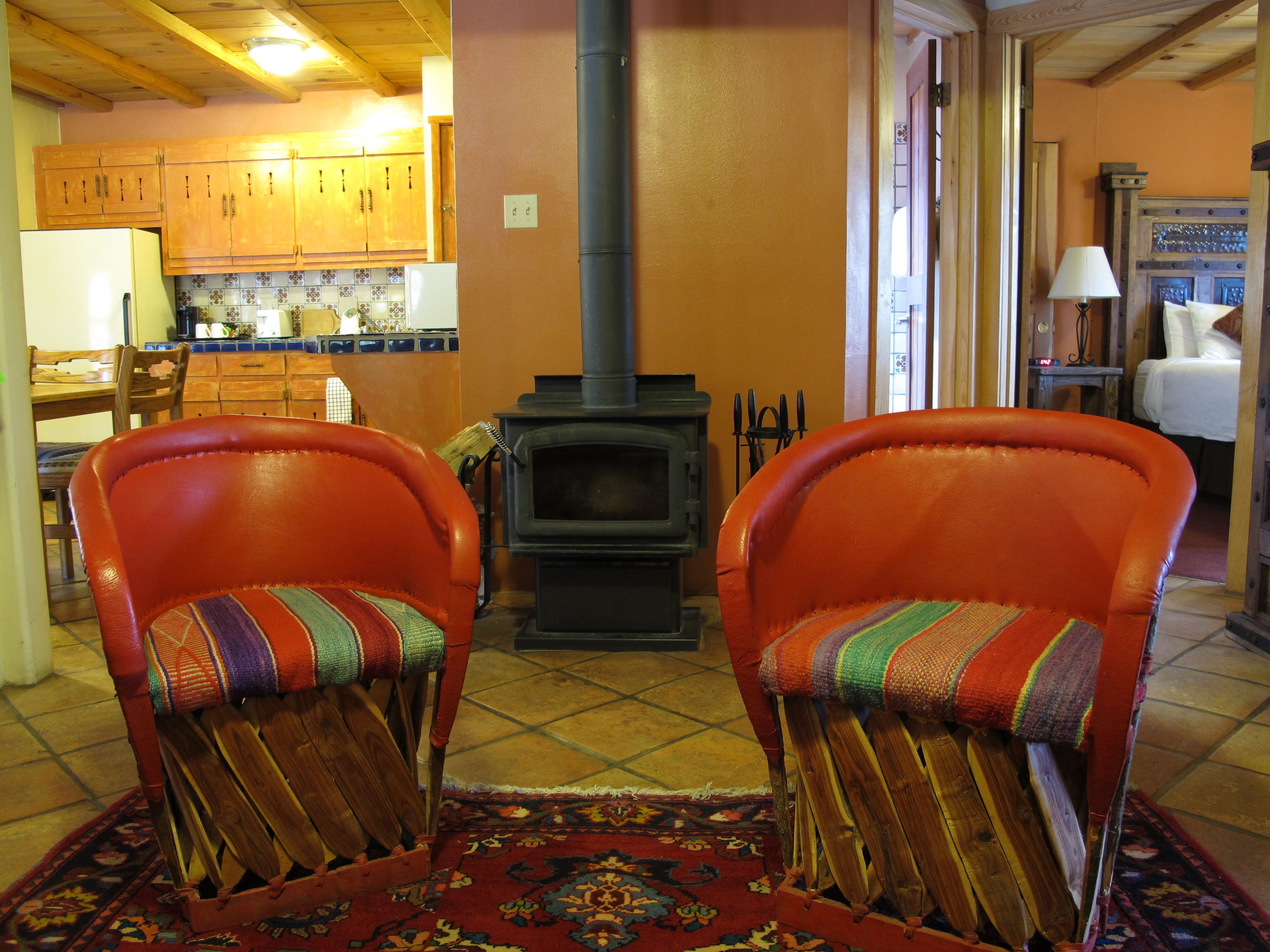 Een gezellige woonkamer met twee leren fauteuils, een open haard, houten kasten en een betegelde vloer.