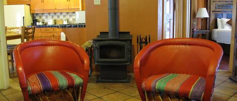 A cozy living room with two leather armchairs, a fireplace, wooden cabinets, and a tiled floor.