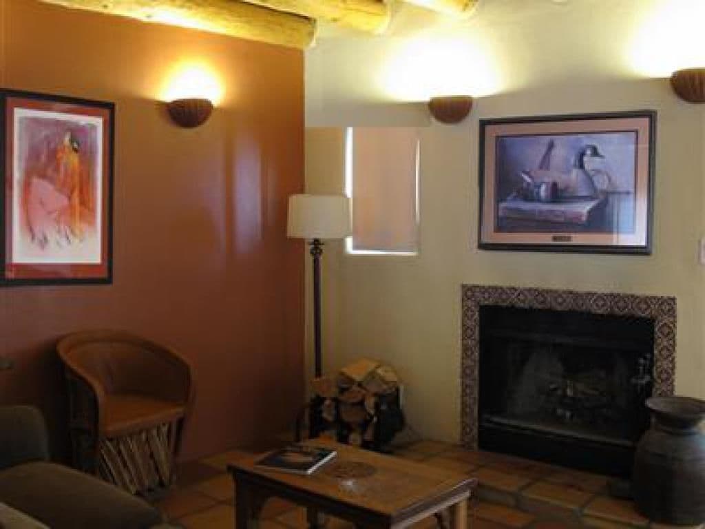 Una sala de estar acogedora con chimenea, un televisor montado en la pared y un cuadro colgado sobre la chimenea.