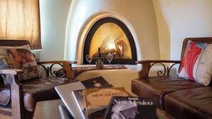 A cozy living room with leather sofas, a fireplace, and books on a coffee table.