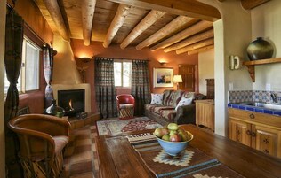 Uma sala de estar acolhedora com lareira, móveis de madeira e um espaço de refeições com uma cesta de frutas.