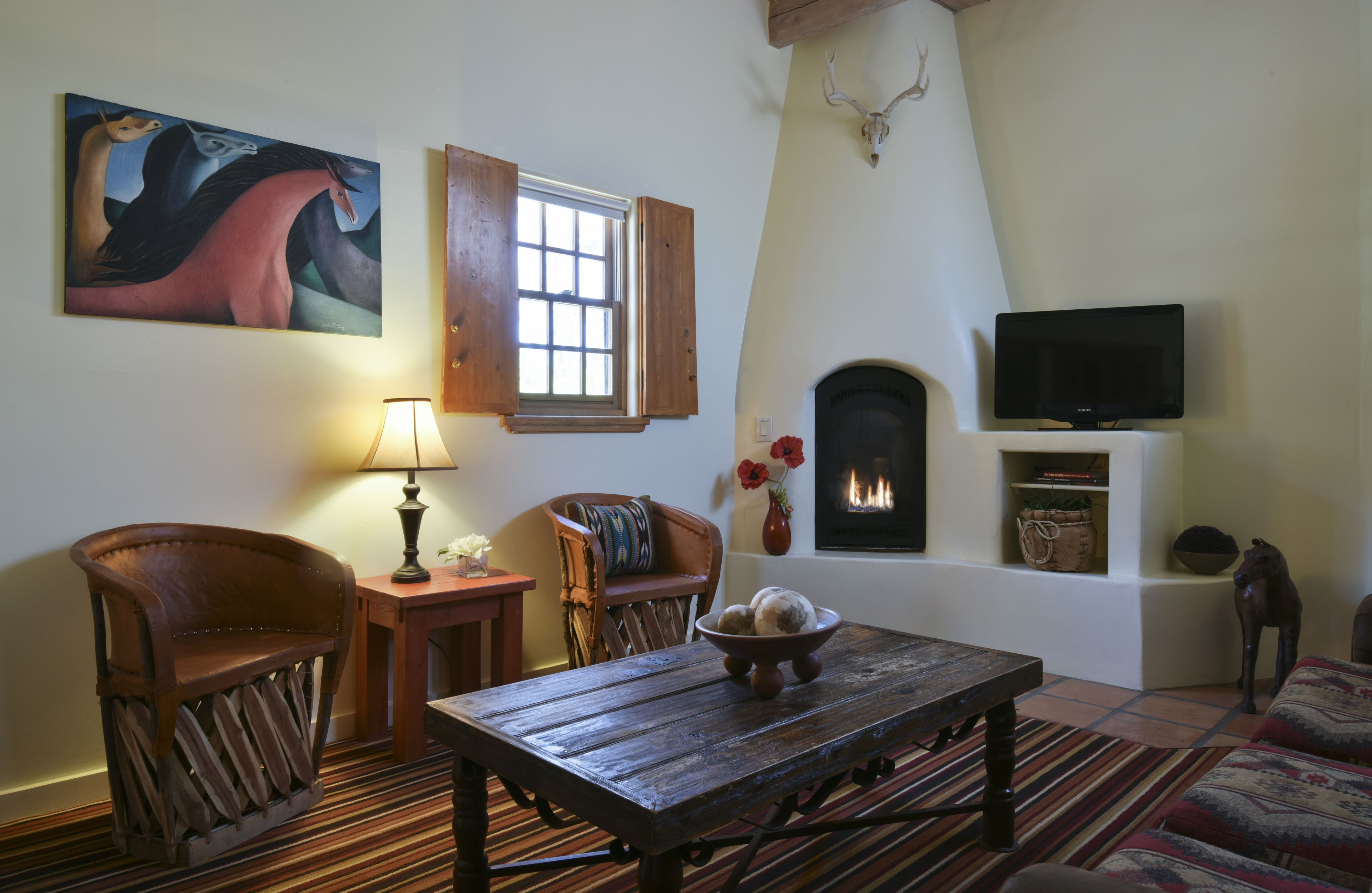 A cozy living room with a fireplace, a television, and a painting on the wall.