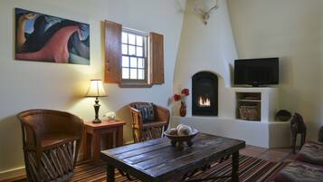 A cozy living room with a fireplace, a television, and a painting on the wall.
