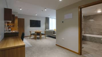 Een moderne hotelkamer met een houten bureau, een zithoek, een bank en een badkamer met een marmeren douche.