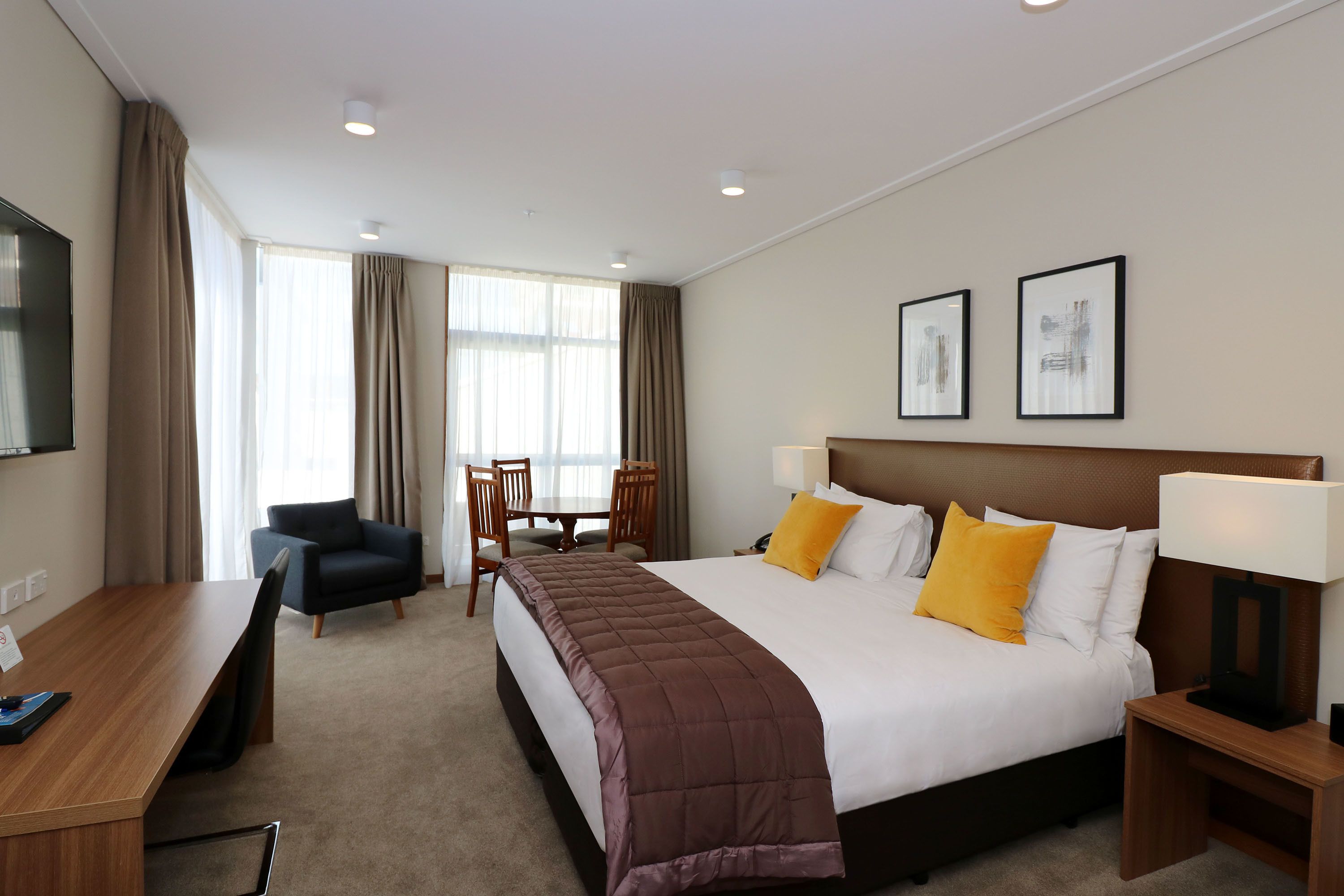 A hotel room with a bed, a desk, a chair, and a TV.