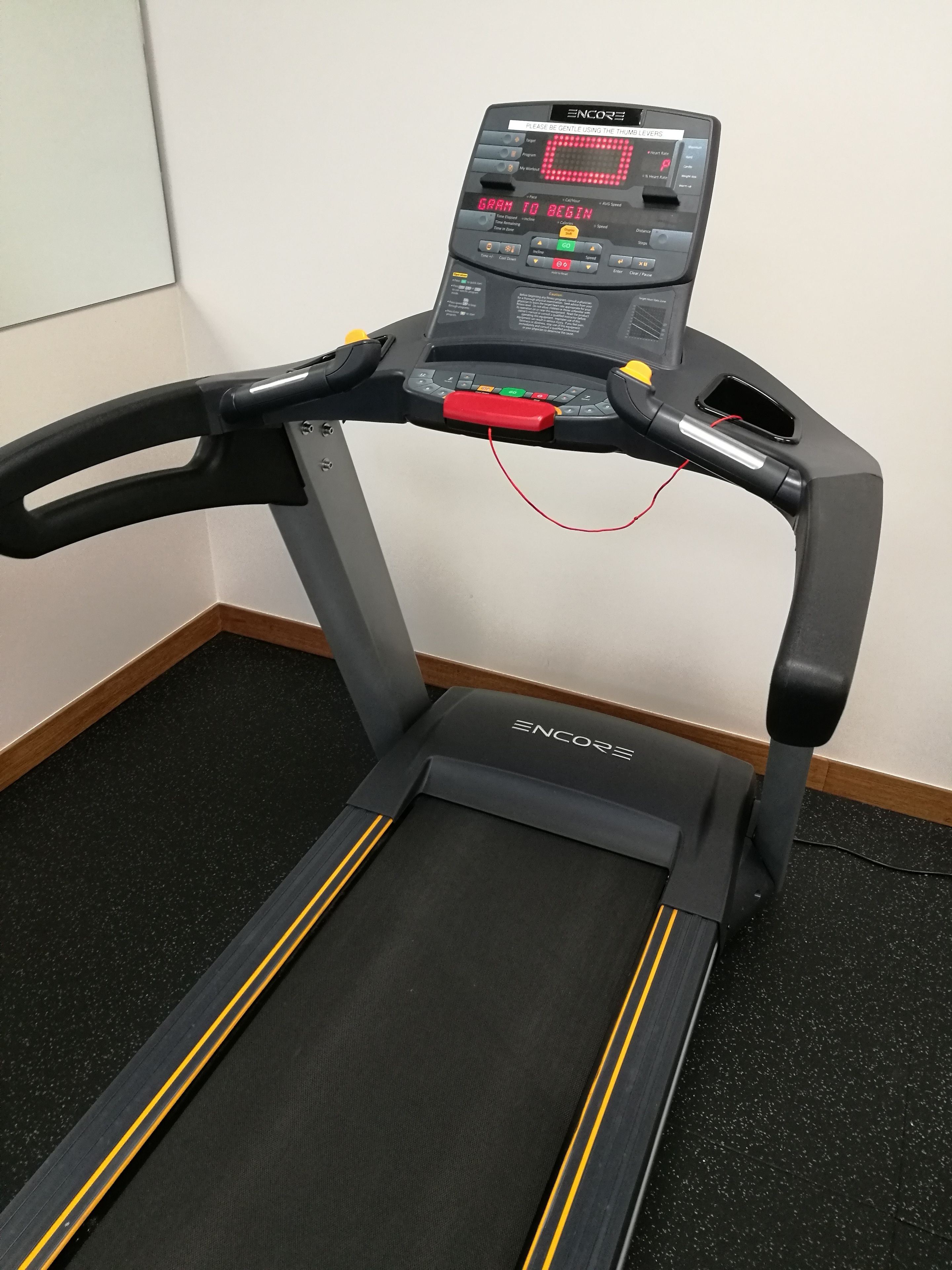 A treadmill with a digital display, control panel, and safety features.