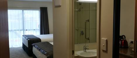 A hotel room with a bed, a bathroom with a sink, and a large window.