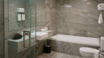 Un baño moderno con ducha de vidrio, lavamanos blanco, bañera y retrete.
