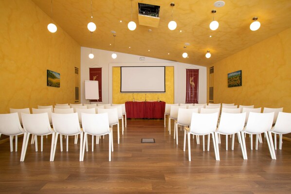 A conference room with white chairs arranged in rows, a red table at the front, and a projector screen. - Best Western Ai Cavalieri Hotel (Palermo)