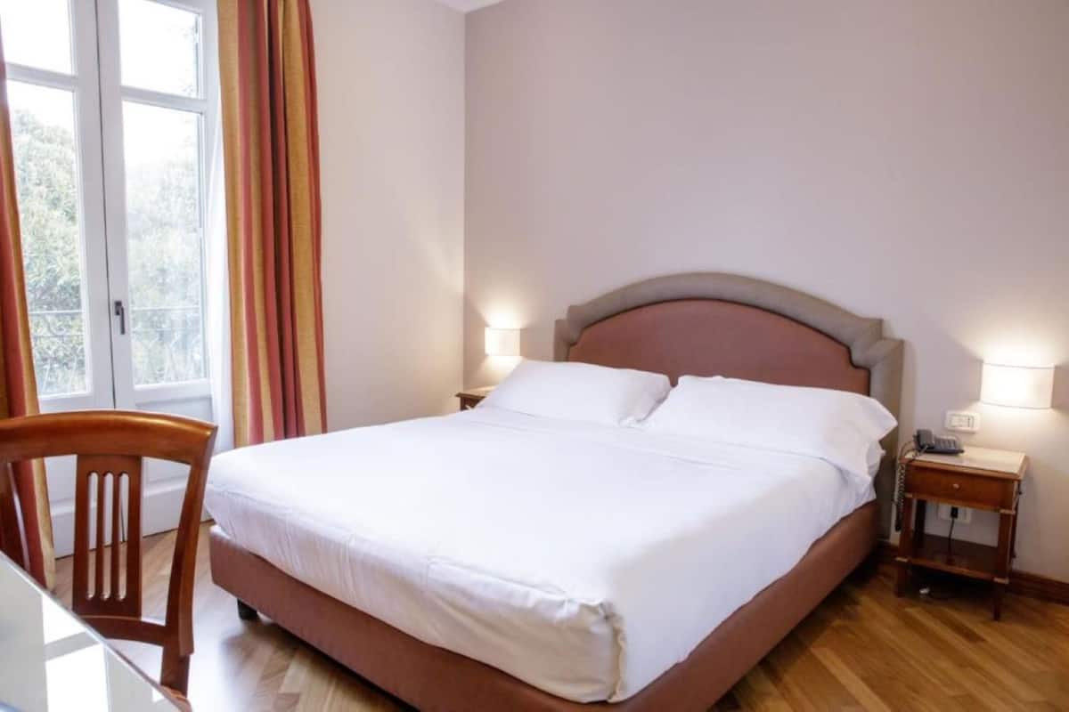 A neatly arranged bedroom with a bed, bedside tables, and a chair.
