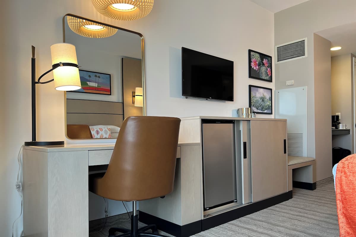 Une chambre d’hôtel équipée d’un bureau, d’une chaise, d’une télévision et d’un mini-bar.