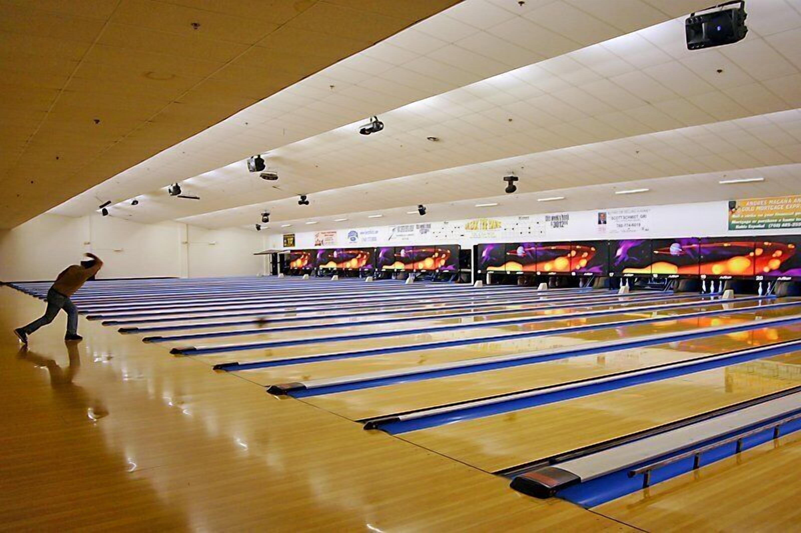 A bowling alley with multiple lanes and a person bowling.