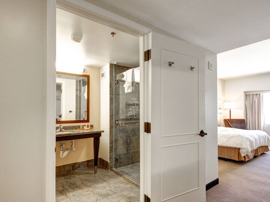 A hotel room with a bathroom, a bed, and a window.