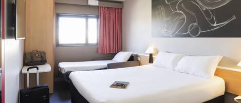 A hotel room with two beds, a desk, a suitcase, and a large abstract painting on the wall.