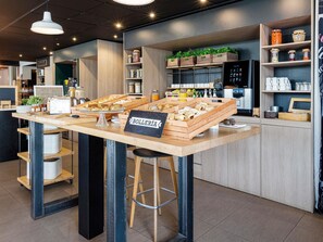 A breakfast bar with wooden crates of pastries, a sign reading 'BOLLERÍA', and a coffee machine. - ibis Valencia Bonaire Aeropuerto (Quart de Poblet)