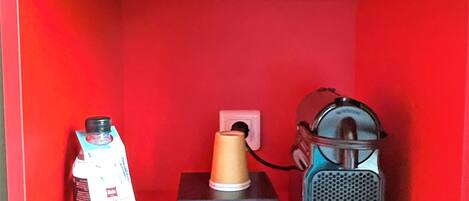 A red shelf with a water bottle, a small jar, and a portable speaker.