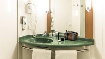 Un baño con un lavabo verde, un espejo, un perchero y un secador de manos.