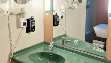 A bathroom with a green sink, a mirror, a hairdryer, and a towel rack.