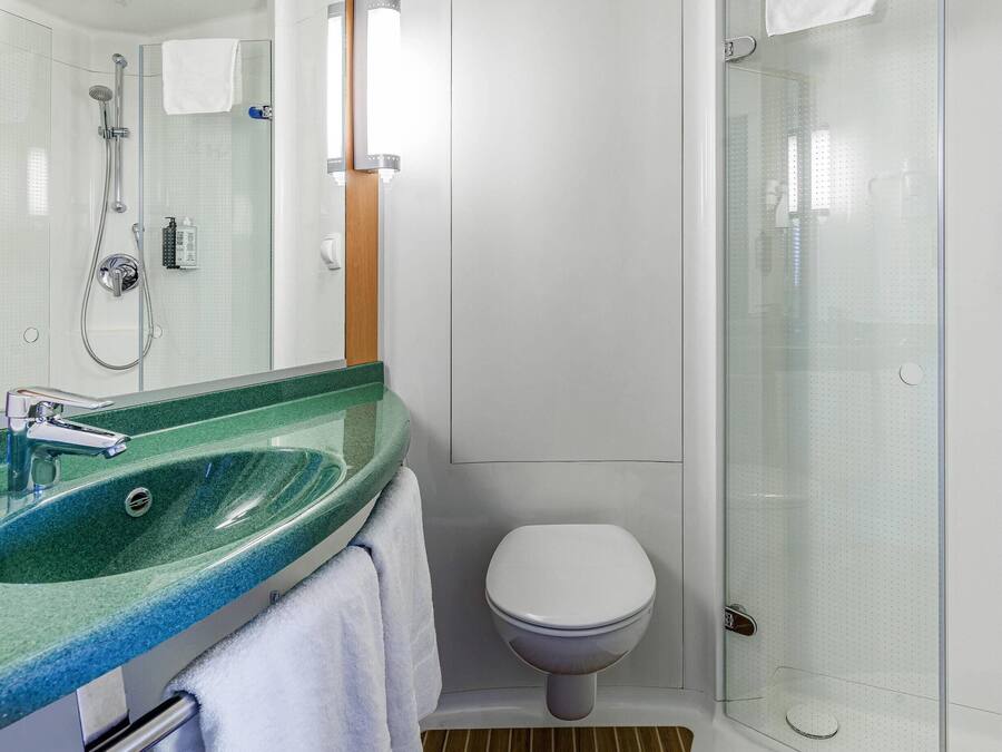 Un baño moderno con cabina de ducha de vidrio, inodoro blanco y lavabo de mármol verde.