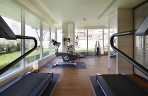 Une salle de sport moderne équipée de vélos d’appartement, de tapis de course et de tapis de sol pour les exercices.